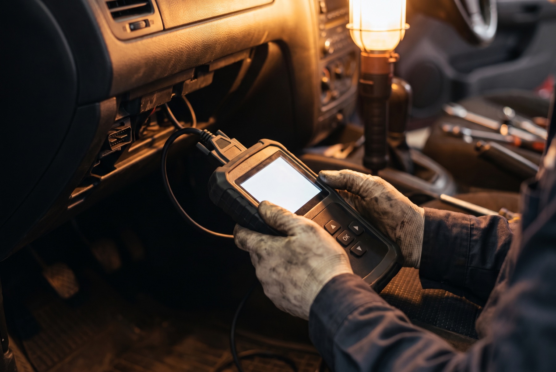 A Trueline technician running a diagnostic scan under the dashboard of a customer's vehicle.